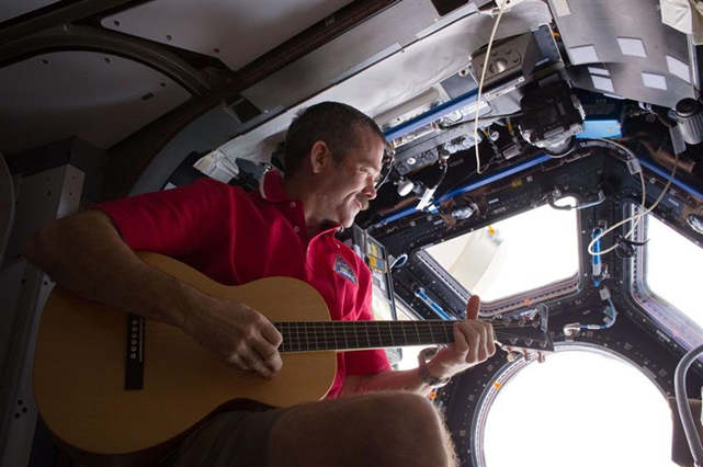 Col. Chris Hadfield strumming his guitar in the ISS Cupola module